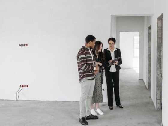 Un couple étudie des documents avec une professionnelle de l’immobilier dans un logement. Photographie d’illustration.