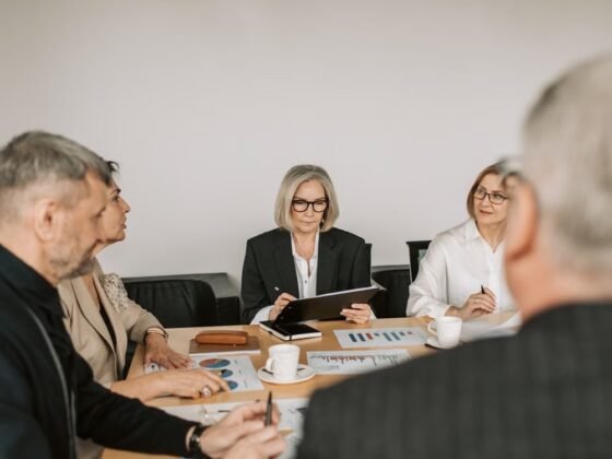 Professionnels expérimentés réunis autour de documents et de graphiques pour préparer une décision d’entreprise.