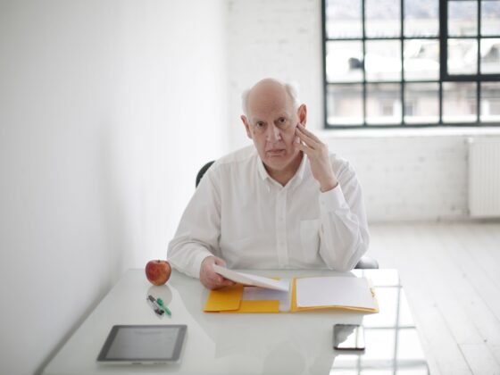 Homme mûr pensif devant des dossiers sur son bureau — photographie d’illustration.