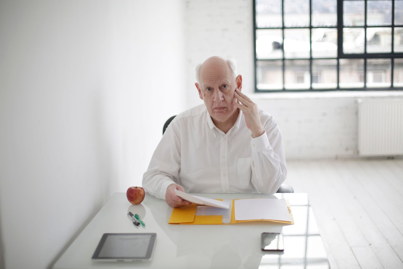 Homme mûr pensif devant des dossiers sur son bureau — photographie d’illustration.