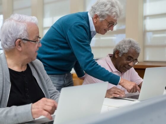 Trois adultes expérimentés apprennent ensemble à utiliser des ordinateurs dans une salle de formation. Photographie d’illustration.